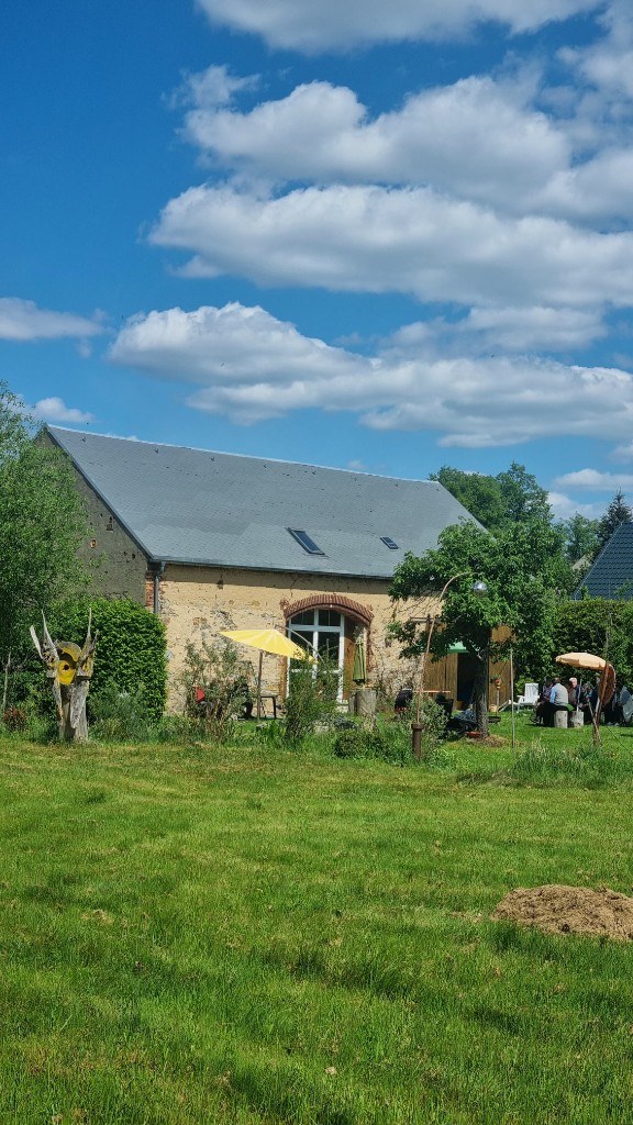 Kulturscheune und Garten unter blauem Himmel